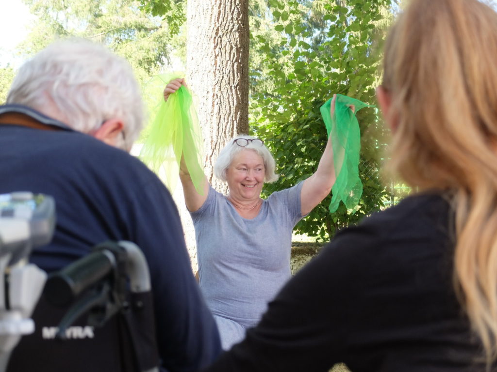 Ältere Dame schwingt grüne Tücher